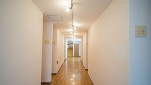 A corridor with wooden flooring and white walls, leading to a staircase. - Hostel KIKO (Sendai)