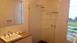 A bathroom with a sink, mirror, and shower.