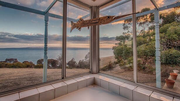 Ett rum med stora fönster som erbjuder utsikt över havet och kullarna.