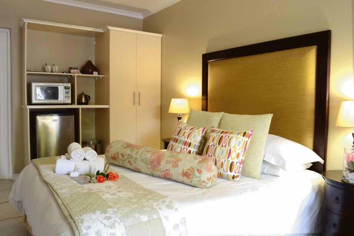 A neatly made bed with floral bedding, a microwave, and a minibar in a hotel room.