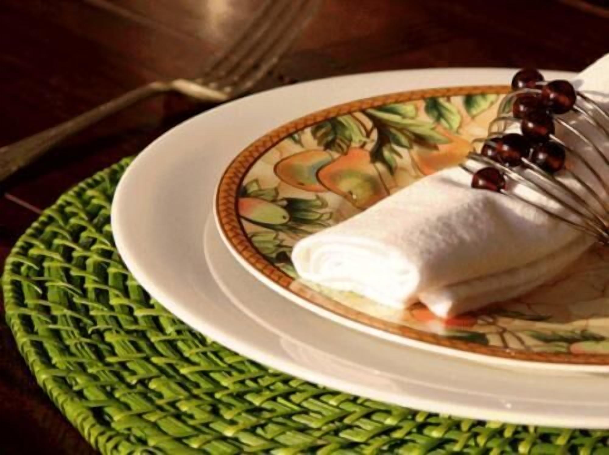 A plate with a rolled item and a decorative plate with a fruit pattern.