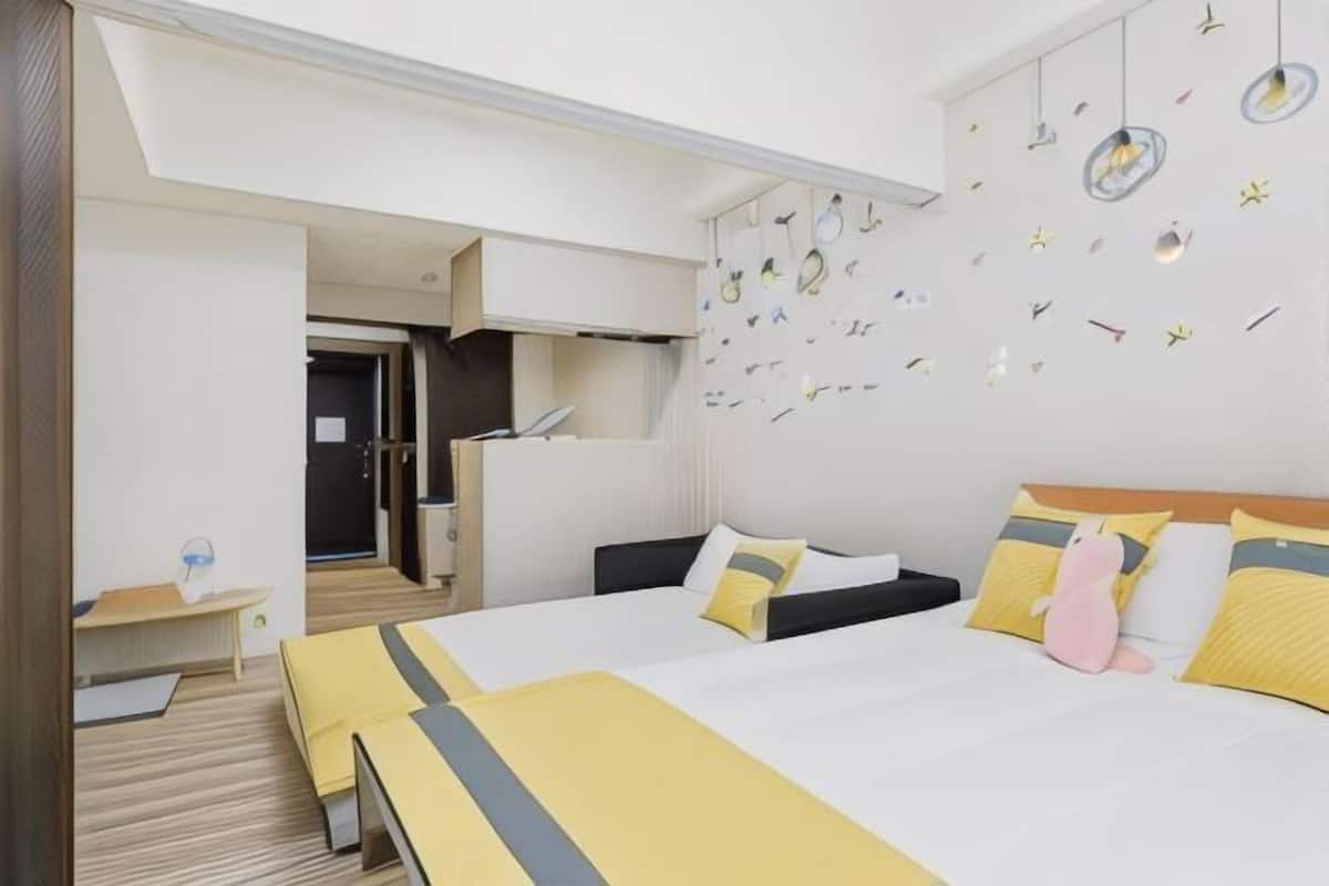 A hotel room with a large bed, a desk, and a kitchenette.