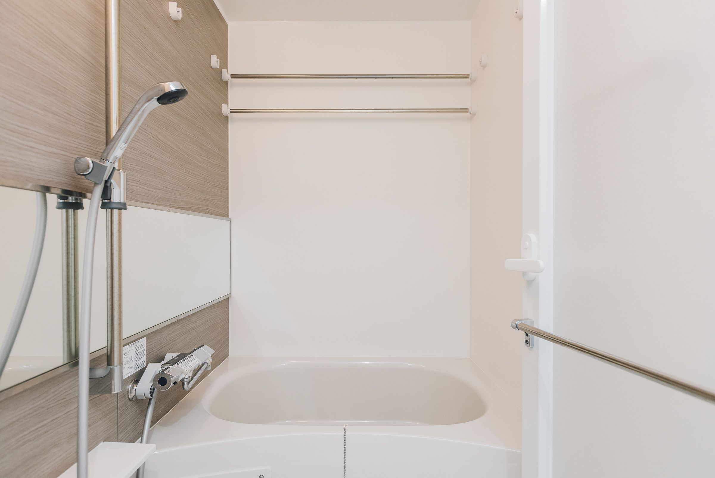 Une salle de bain moderne avec une baignoire blanche, une douchette à main et un porte-serviettes.