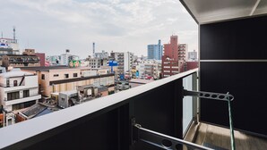 A cityscape view from a balcony with a metal railing and a black door. - AFP Tennoji Apartment (Osaka)