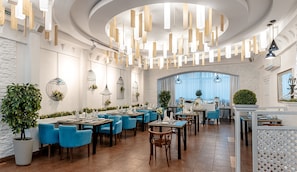 Enjoy a casual yet elegant dining experience in this inviting space with curved ceilings, textured walls, and natural greenery.