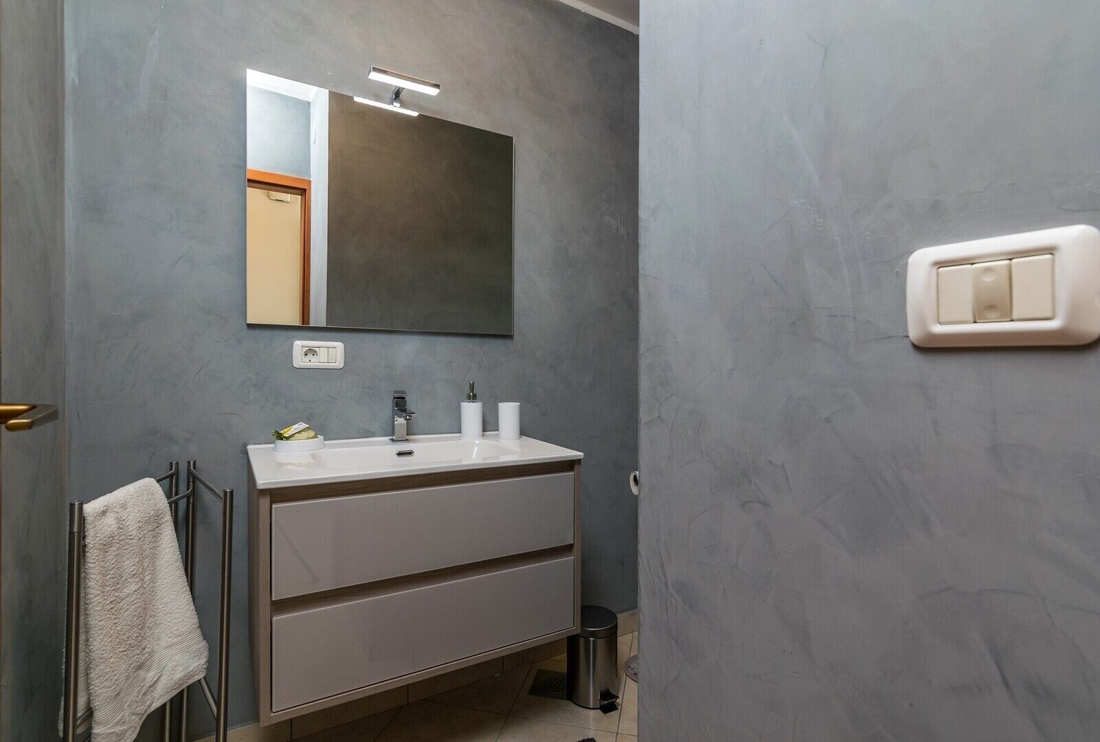 Une salle de bain avec un lavabo blanc, un miroir et un porte-serviettes.