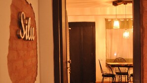 Un couloir mène à une salle à manger dotée d’un plancher en bois, d’une table avec des chaises et d’un luminaire suspendu.