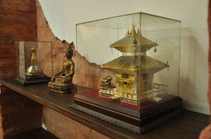 Una vitrina que contiene una estatua dorada de Buda, una estatua más pequeña de Buda y un modelo a escala de un templo.