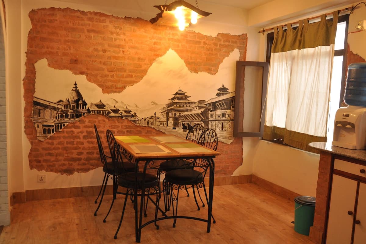 A dining area with a mural of a traditional building, a table with chairs, and a window with curtains.