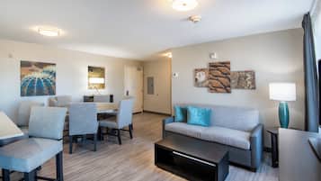 A modern hotel room with a dining area, a sofa, and a coffee table.