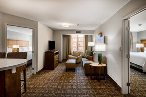 A hotel room with a bed, a desk, a chair, a sofa, a small table, and a TV. - Staybridge Suites Scottsdale - Talking Stick by IHG (Scottsdale)