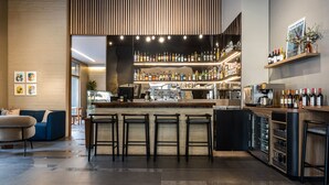 Un área de bar moderna con mostrador, varios taburetes y una amplia variedad de botellas y copas.