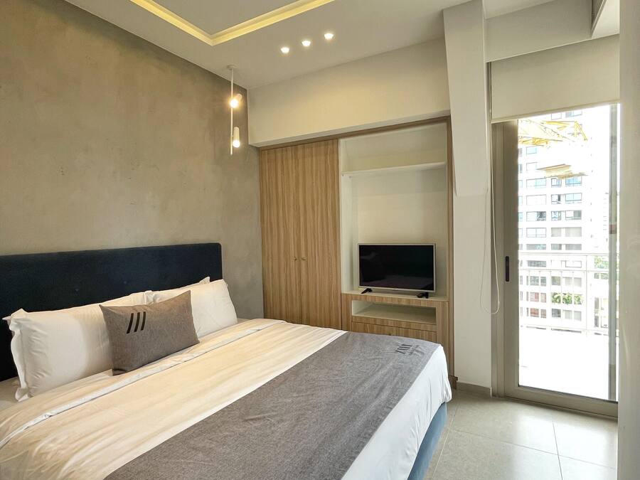 Quarto de hotel moderno com uma cama grande, televisão de tela plana e porta de vidro deslizante para a varanda.