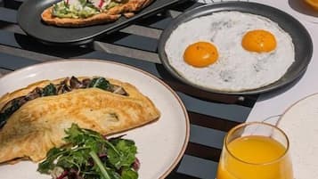 Ein Tisch mit Frühstücksartikeln, darunter Eier, ein Gebäckstück und ein Glas Orangensaft.