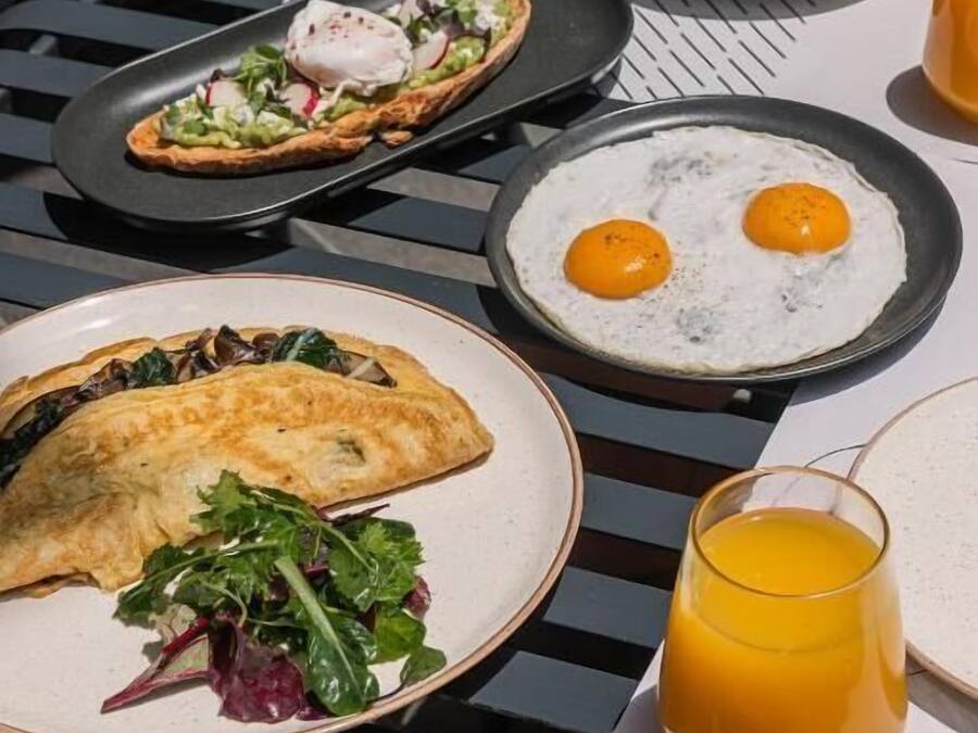 Ein Tisch mit Frühstücksartikeln, darunter Eier, ein Gebäckstück und ein Glas Orangensaft.