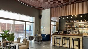 Zona de bar moderna con barra, taburetes y una gran variedad de botellas.