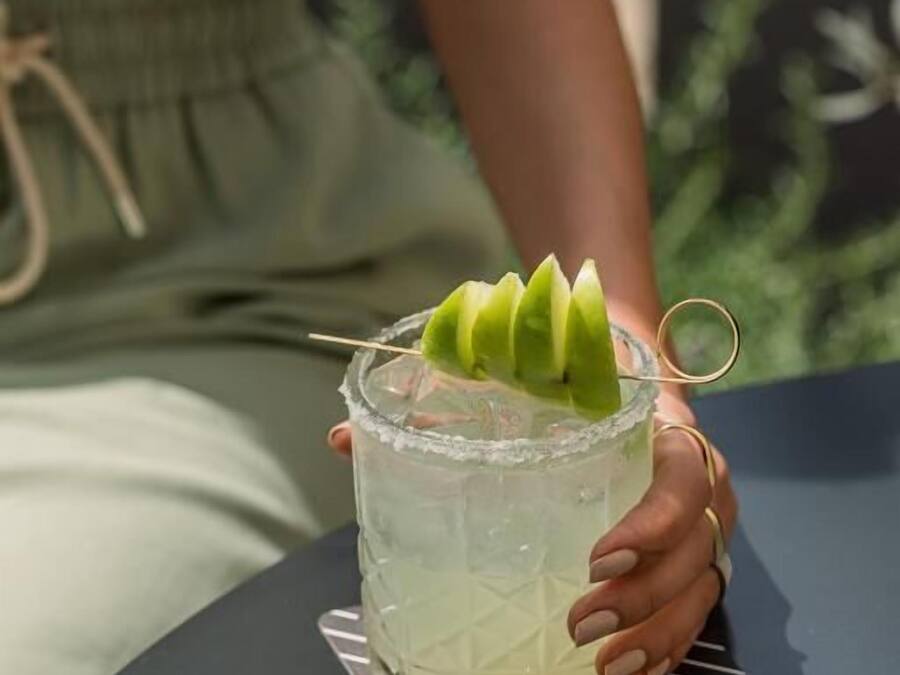 Una persona sosteniendo un vaso con una guarnición verde.