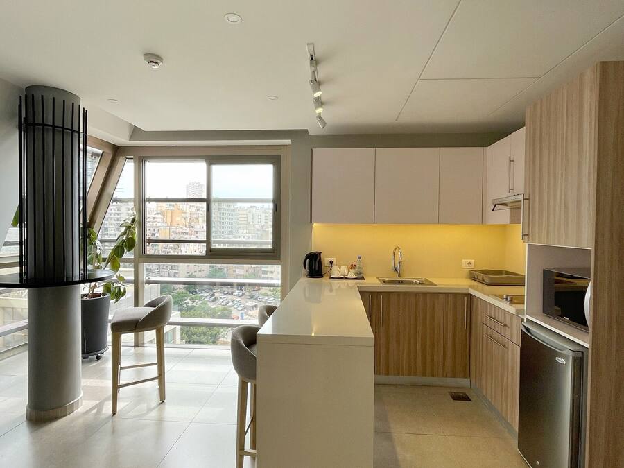 Una cocina moderna con una isla central, armarios de madera y un amplio ventanal con vistas a la ciudad.