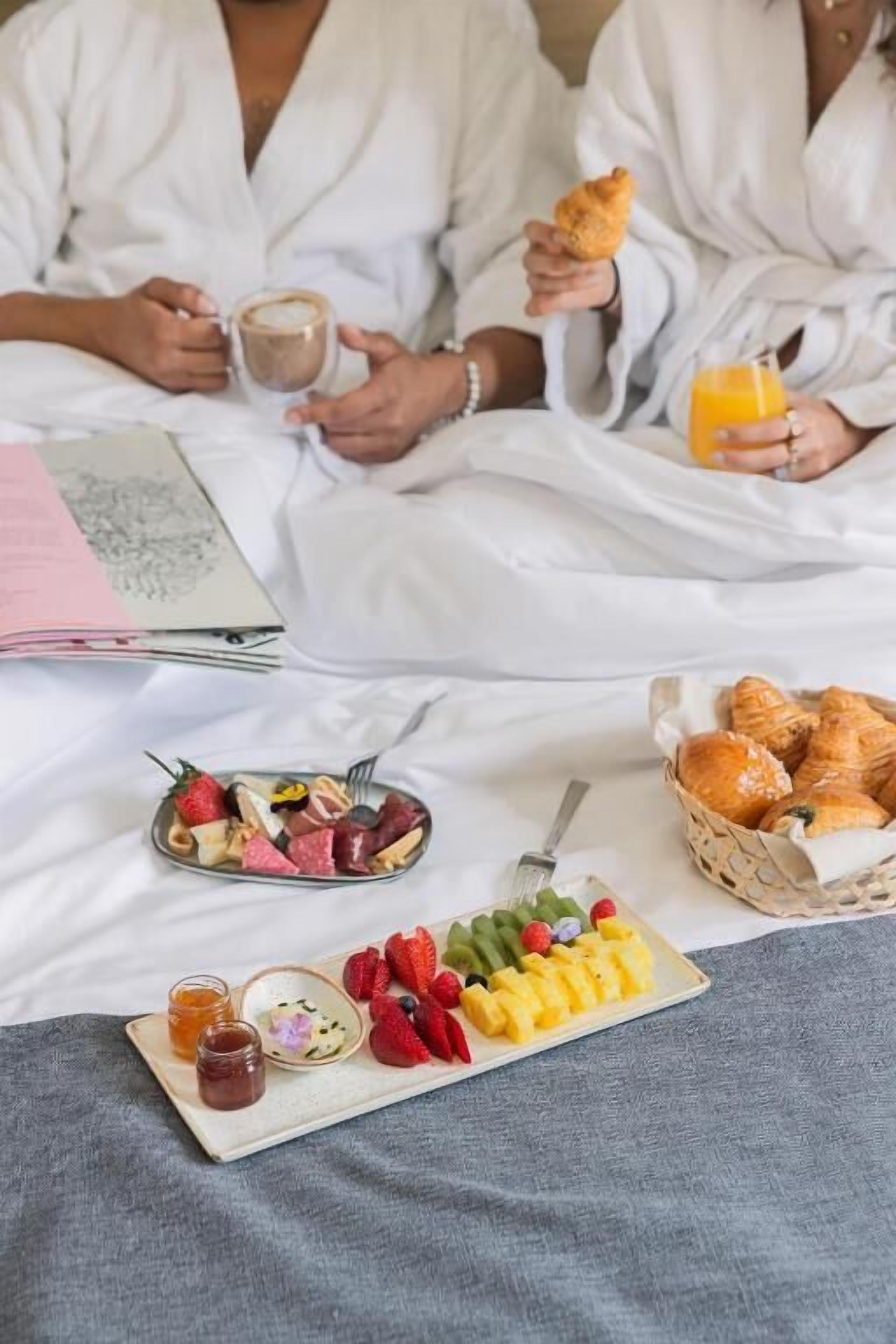 A breakfast setup with croissants, fruit, and a variety of cheeses and meats on a tray.