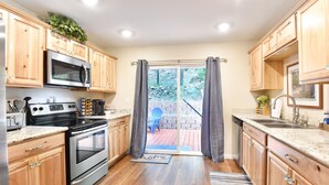 Une cuisine dotée de meubles en bois, d’appareils électroménagers en acier inoxydable et d’une porte-fenêtre coulissante donnant sur un patio.
