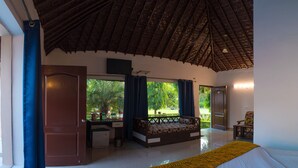 Una habitación amplia con cama, escritorio y vista a un jardín.
