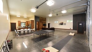 Una habitación amplia con mesa de ping pong, comedor con sillas y cocina con armarios.