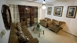 Ein Wohnzimmer mit zwei Sofas, einem Glastisch und einem Deckenventilator.