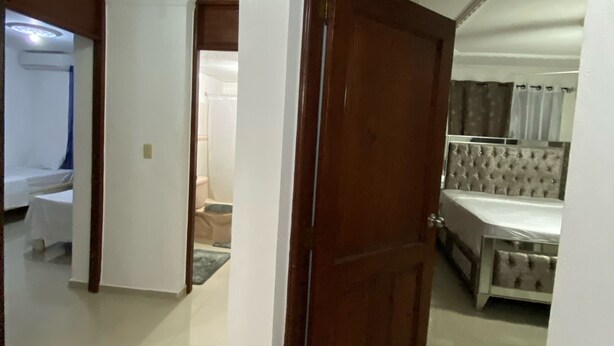 Ein Hotelzimmer mit Bett, Bad und einem Flur, der zu einem anderen Raum führt.