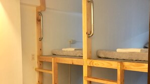 En säng med våningssäng i trä, med handtag i metall, en liten hylla och en handduk på den övre våningen.
