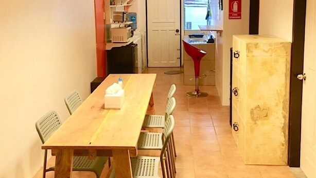En smal hall med ett träbord och stolar, en röd stol och ett skåp.