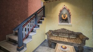 A staircase with a wooden railing, a bench, and a wall-mounted statue. - Villa Tanah Carik (Tegallalang)