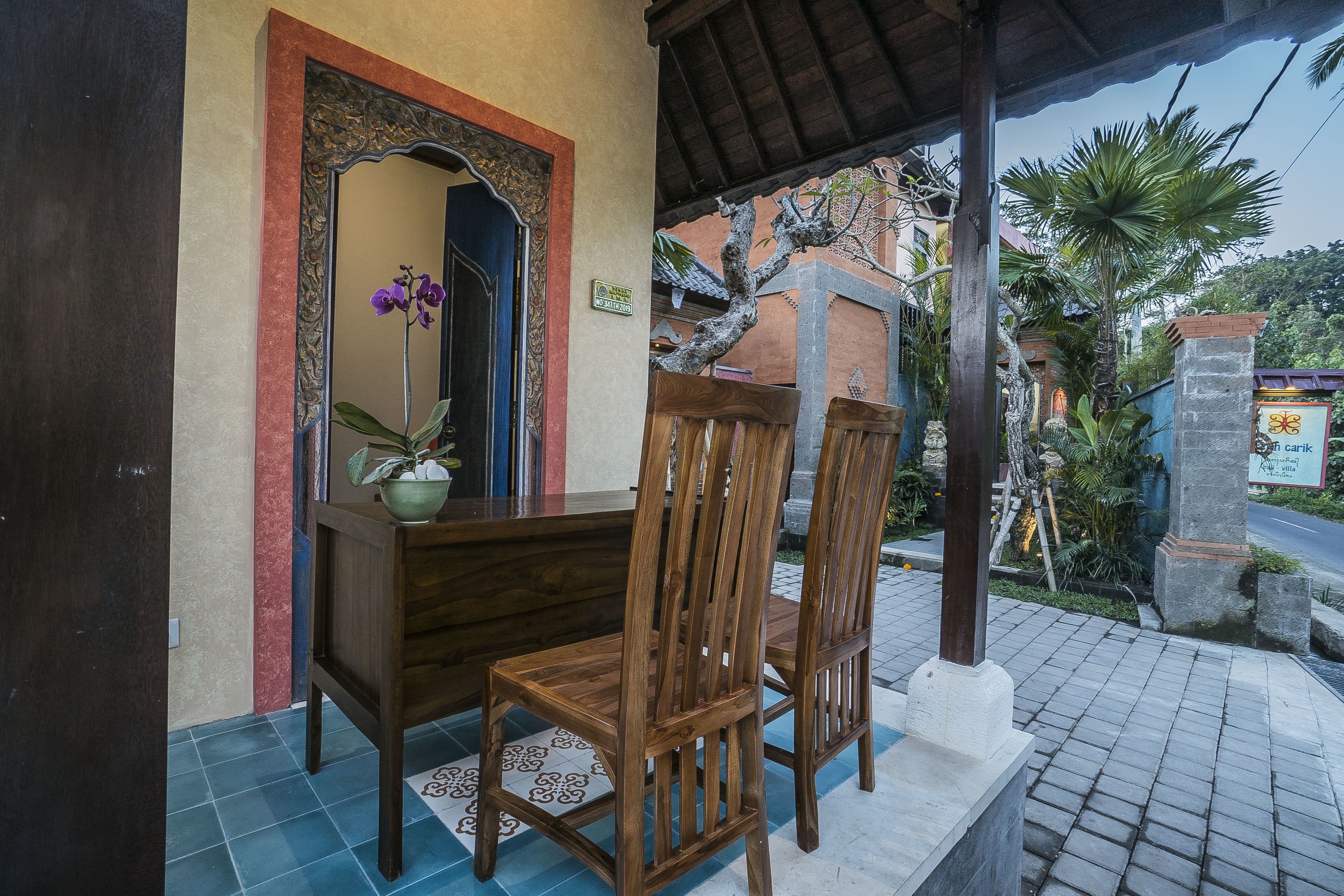 Uma cadeira e mesa de madeira em frente a um edifício com chão de azulejos e um arco decorativo.