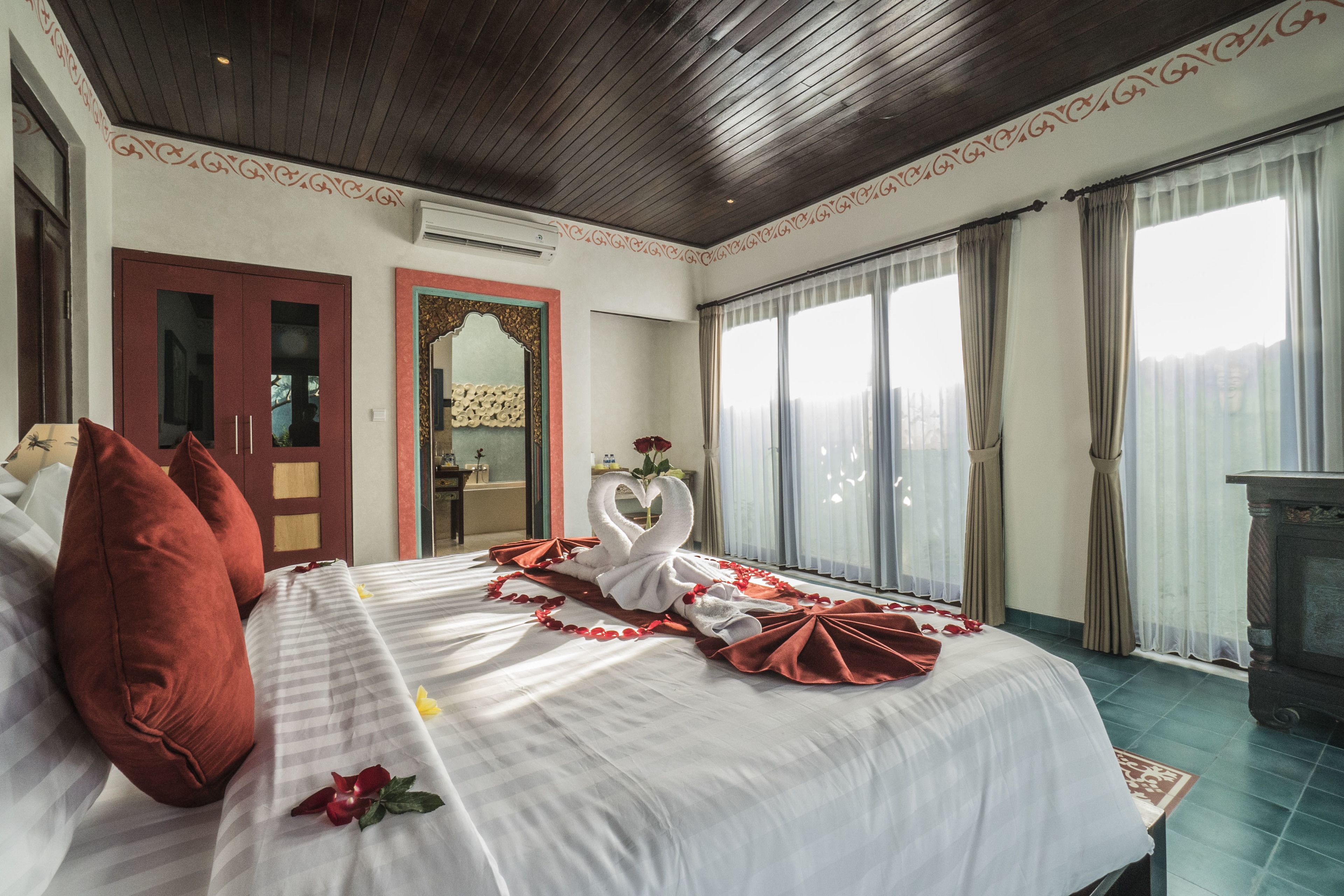 Una habitación de hotel con una cama grande, techo de madera, puerta de vidrio corrediza y chimenea.
