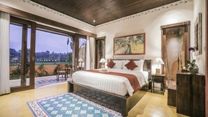 A spacious bedroom with a large bed, a view of the cityscape through a sliding door, and a balcony with a view of palm trees. - Villa Tanah Carik (Tegallalang)