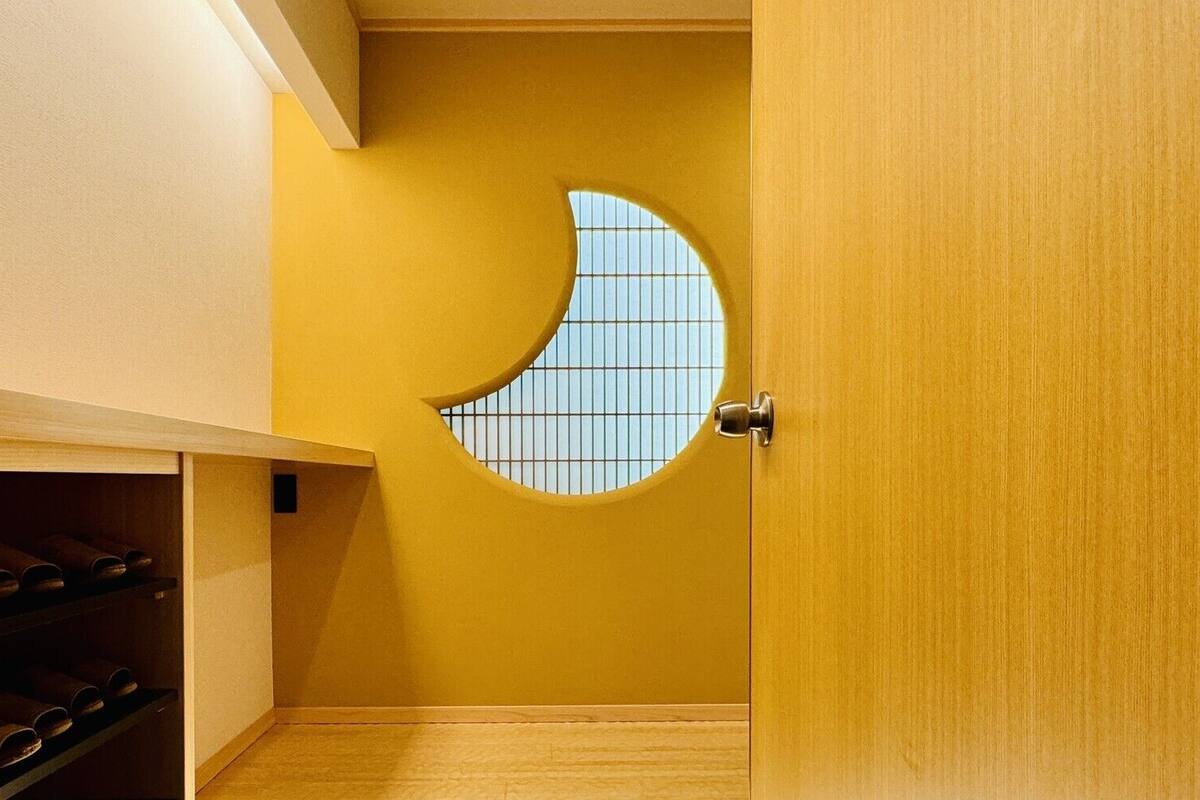 Ein Zimmer mit Holztür, rundem Fenster und Schuhablage.