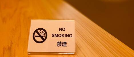 A no smoking sign on a wooden surface.