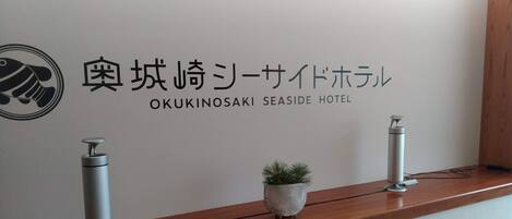 A reception desk at Okukinosaki Seaside Hotel with a logo, Japanese text, and two water dispensers.
