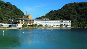 A hotel with multiple floors, a swimming pool, and a mountainous backdrop. - Okukinosaki Seaside Hotel (Toyooka)