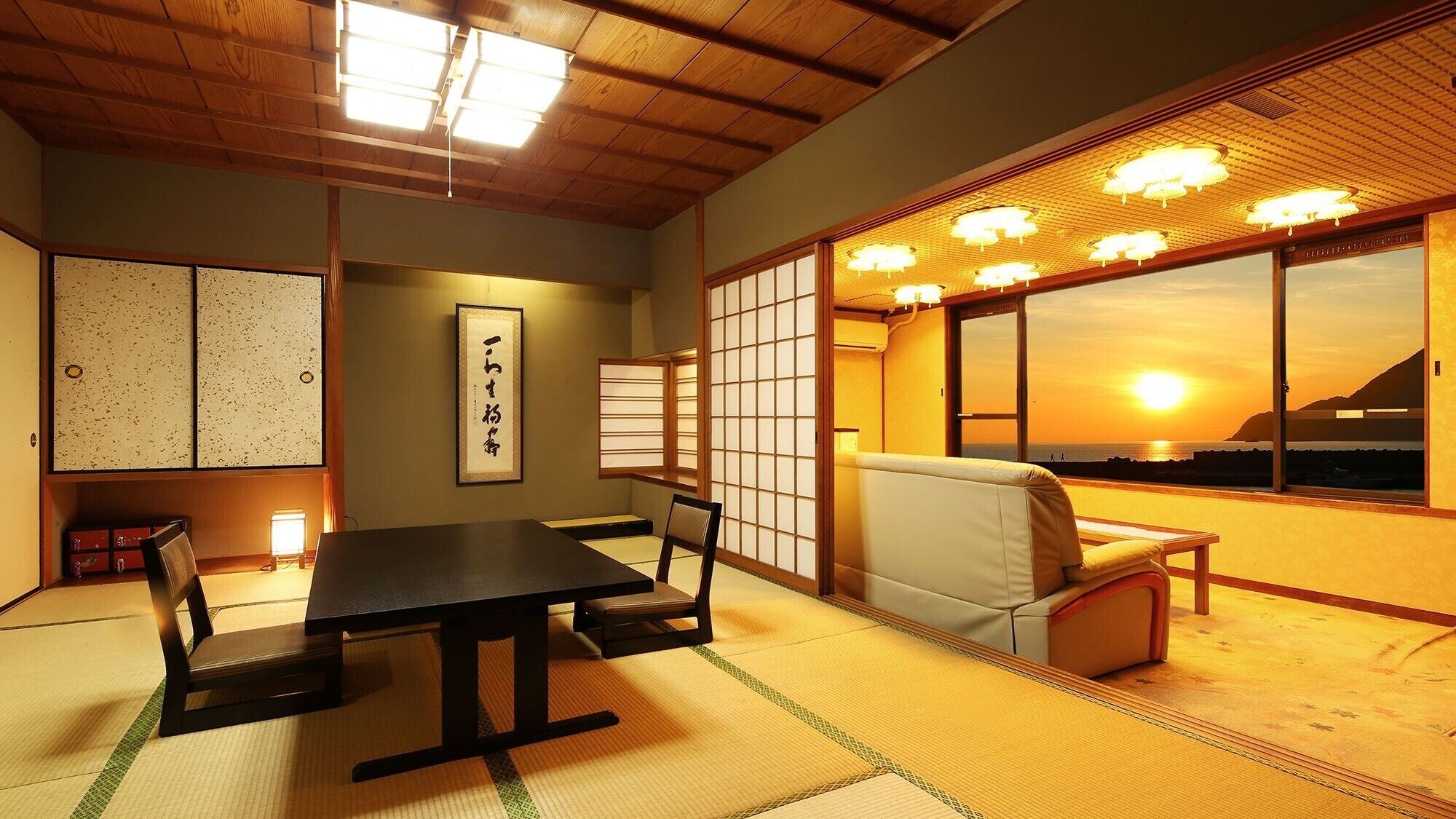 A traditional Japanese room with tatami flooring, a low table, a cushioned bench, sliding doors, and a view of the sunset.