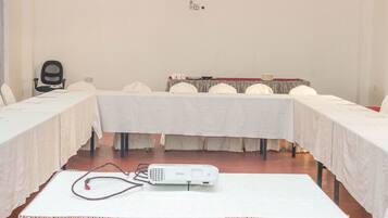 A conference room with a white table, chairs, and a projector on a table.