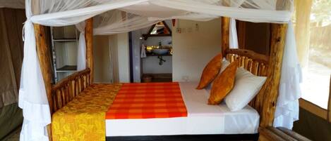 Una cama con dosel de madera, cubierta con un edredón a cuadros rojo y amarillo, y almohadas blancas.