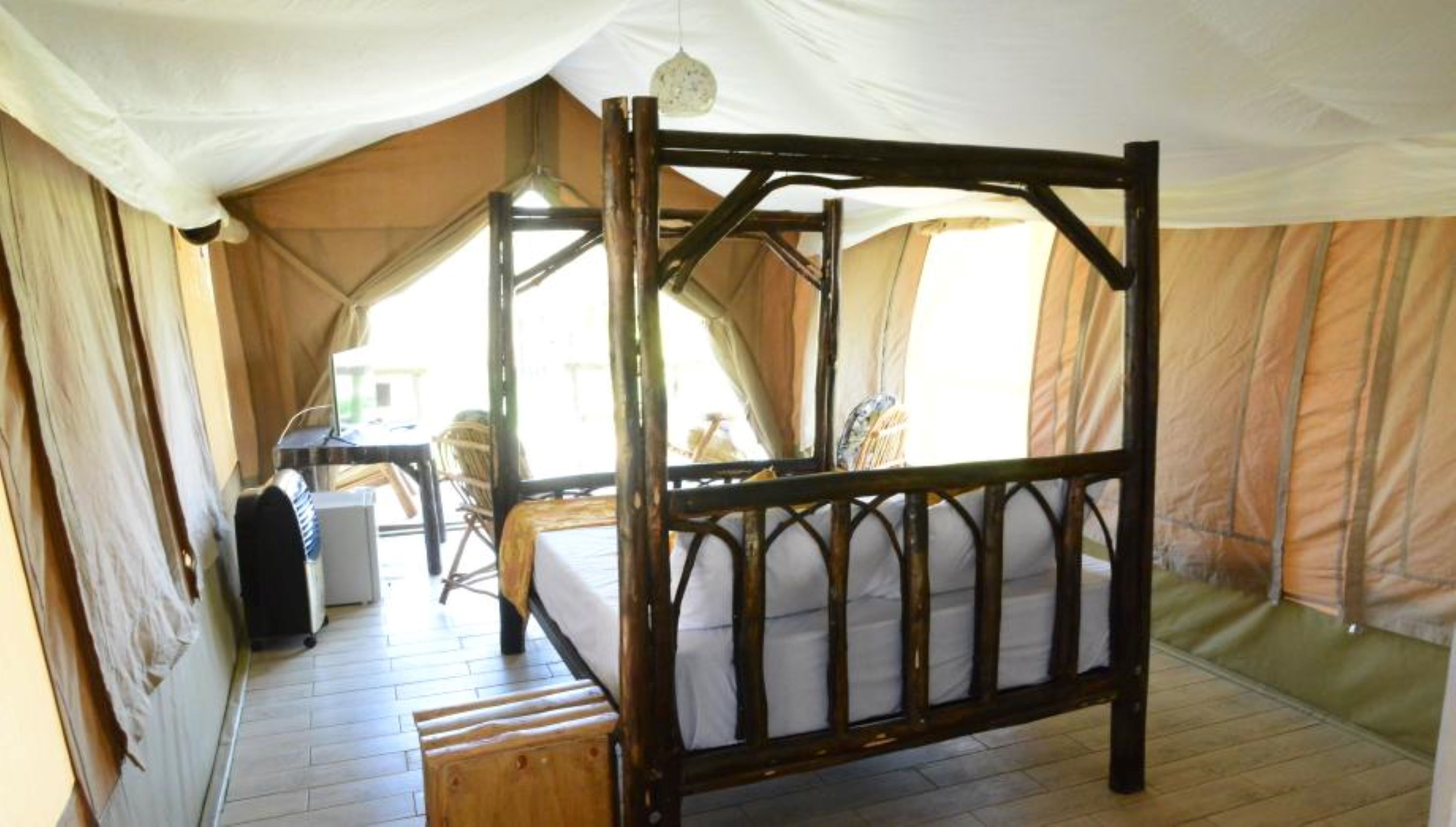 Ein Zelttyp-Zimmer mit einem hölzernen Bett, einem Schreibtisch und einem Stuhl.