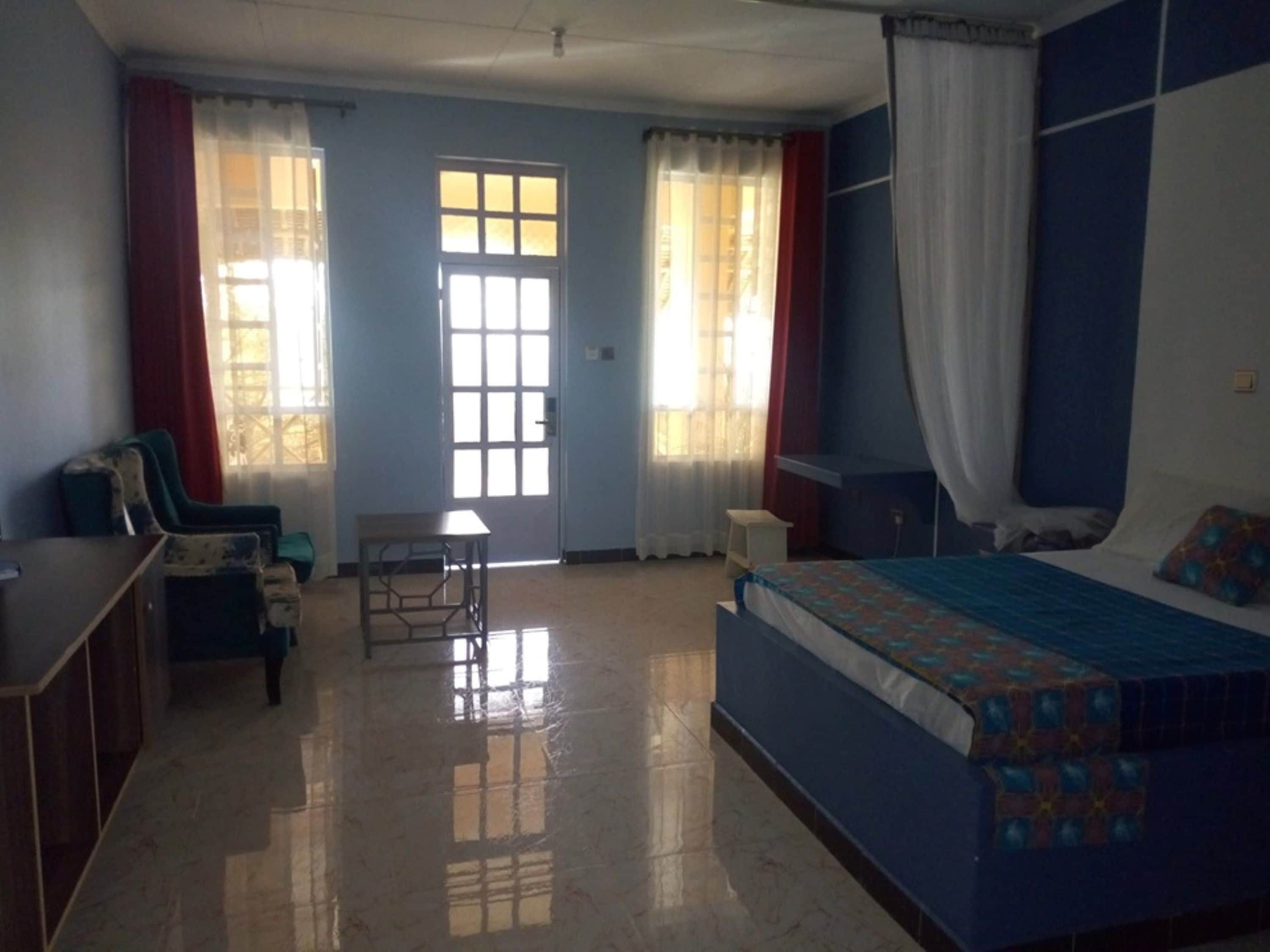 A bedroom with a bed, a desk, a chair, and a window.