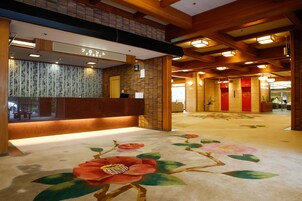 Zona de recepción de hotel con un mostrador de madera, alfombra floral y diseño interior tradicional japonés.