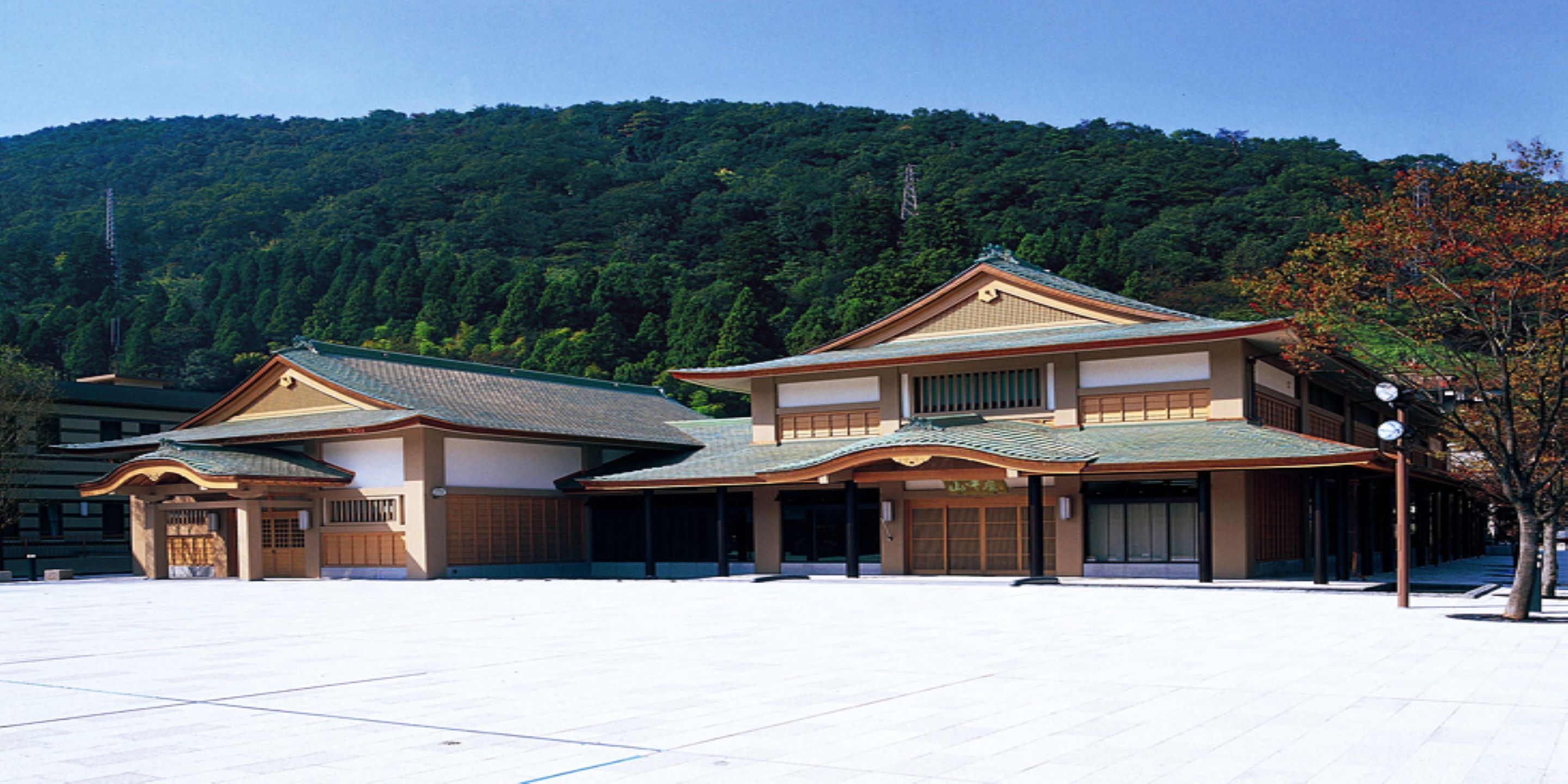A traditional Japanese building with a tiled roof, large windows, and a spacious courtyard.