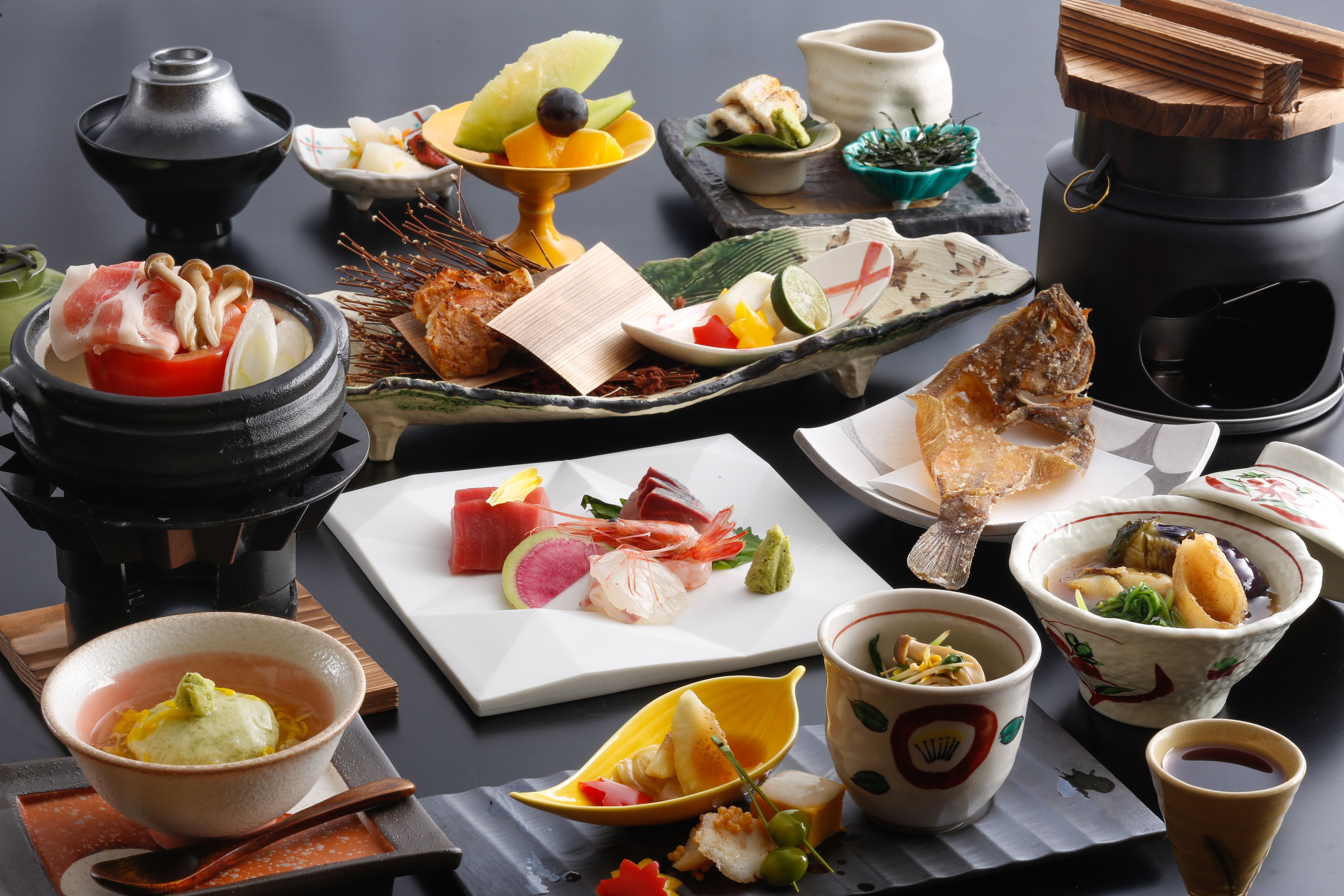 A variety of dishes and a hot pot setup on a table.