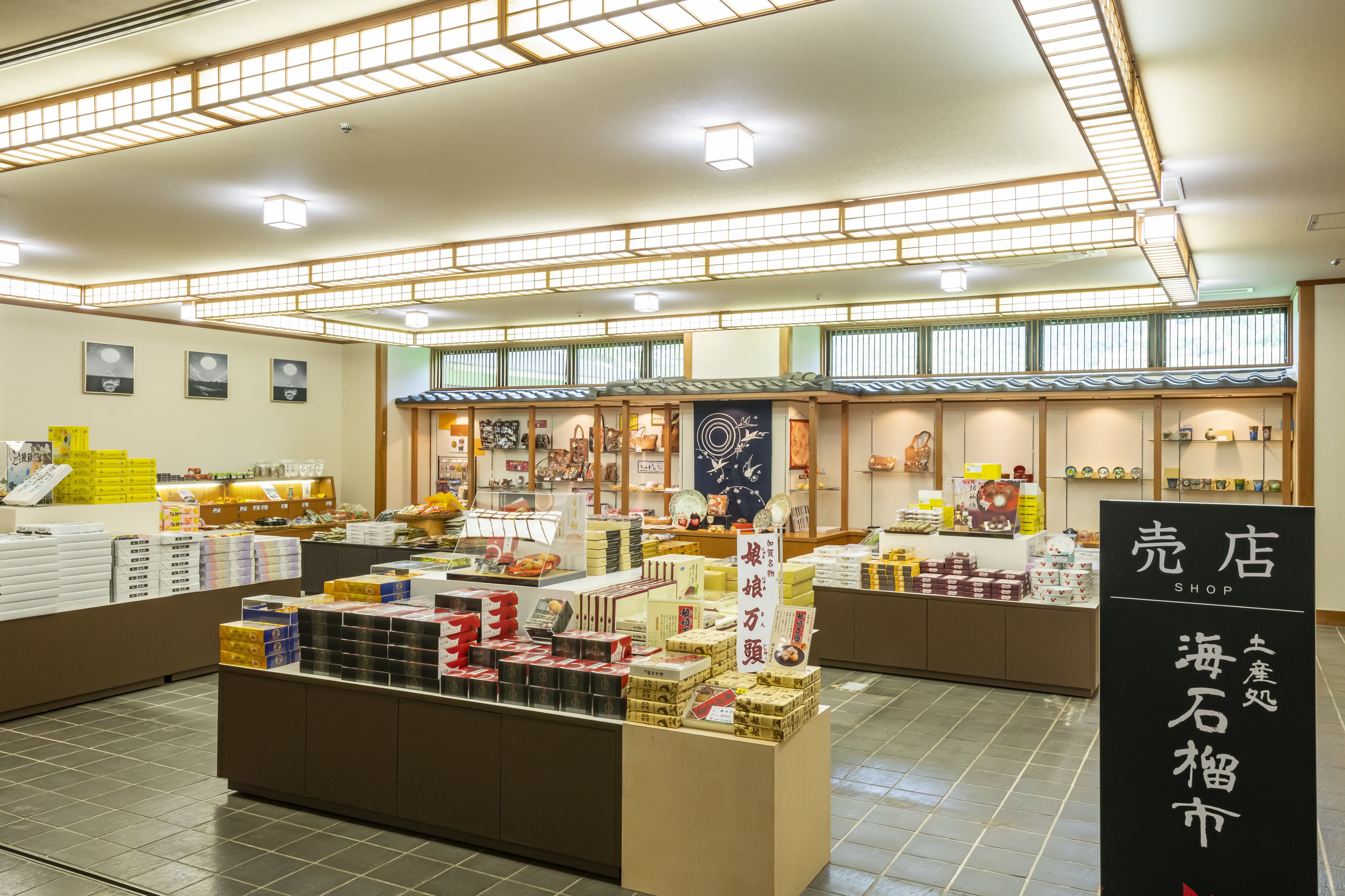 A traditional Japanese shop interior with various packaged goods on display, wooden shelves, and a tiled floor.