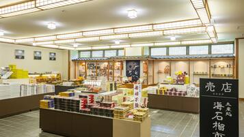 A traditional Japanese shop interior with various packaged goods on display, wooden shelves, and a tiled floor.