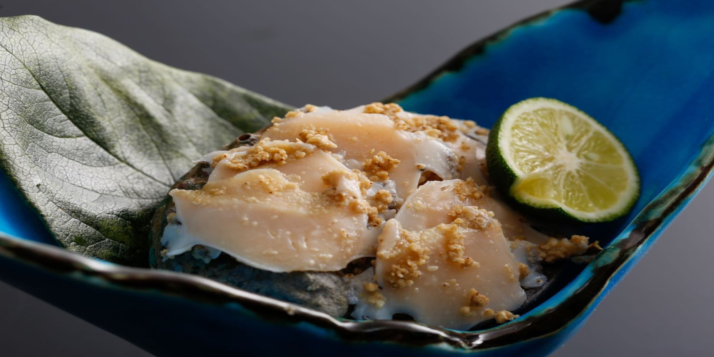 Ein Fischgericht mit einer Limettenscheibe auf einem blauen Teller.