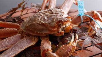 Um caranguejo com uma etiqueta, rodeado de algas marinhas e outros animais marinhos sobre uma superfície de madeira.